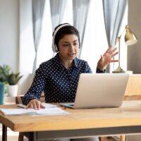 Indian student wear headphones use laptop e-learning remotely by videocall