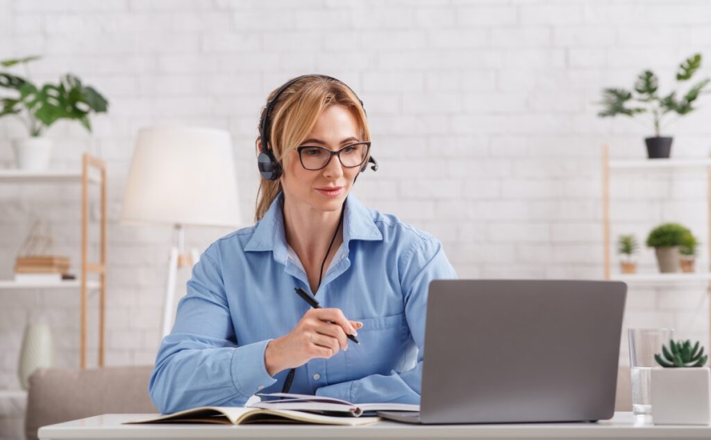 Online consultation with psychologist. Woman with glasses and headphones looks at laptop