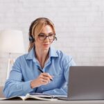 Online consultation with psychologist. Woman with glasses and headphones looks at laptop Online consultation with psychologist. Woman with glasses and headphones looks at laptop