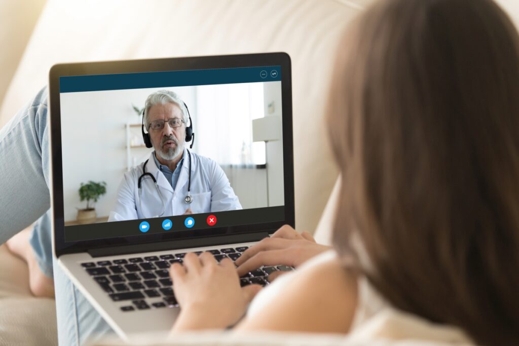 Girl communicating distantly with doctor using webcamera and laptop