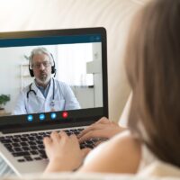 Girl communicating distantly with doctor using webcamera and laptop Girl communicating distantly with doctor using webcamera and laptop