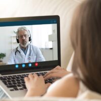 Girl communicating distantly with doctor using webcamera and laptop