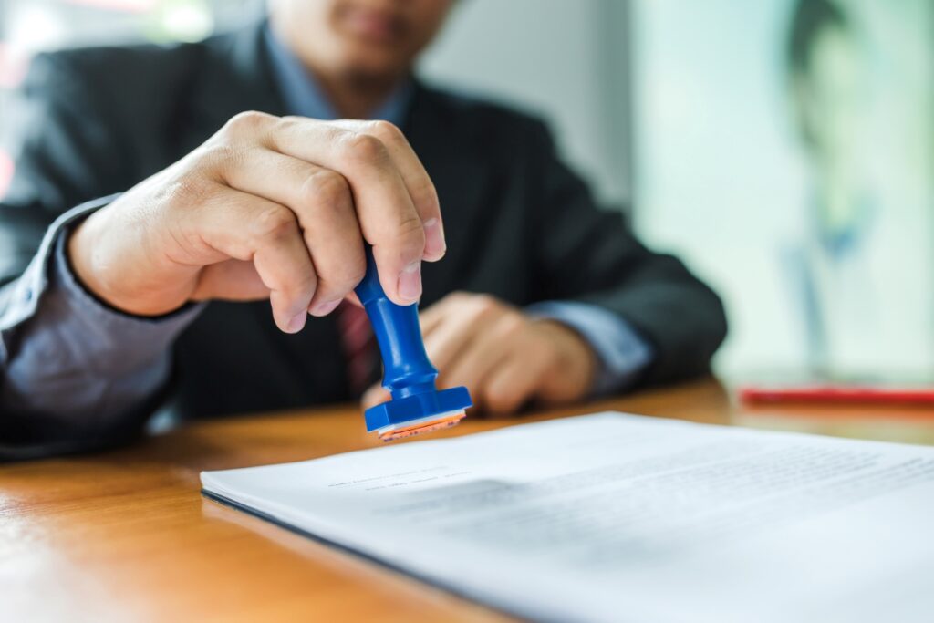 Businessman stamping with approved stamp on document at meeting.