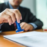 Businessman stamping with approved stamp on document at meeting.